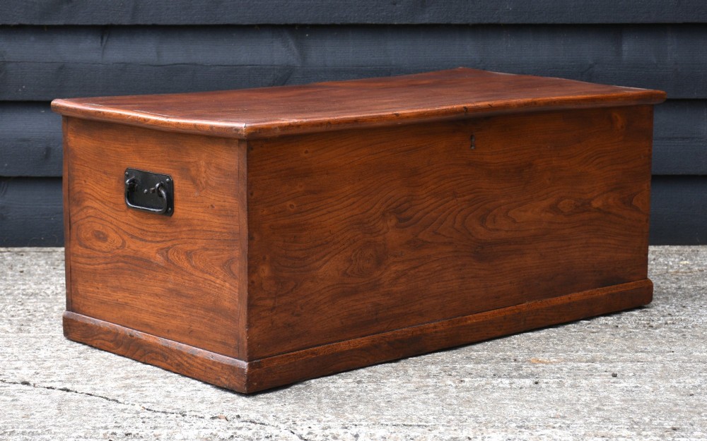 A rectangular Georgian elm blanket box featuring a hinged top lid, front keyhole, side iron handles, and a simple plinth base. View IV