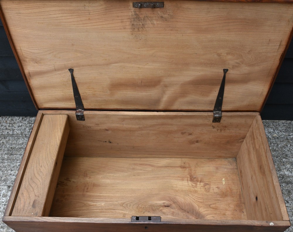A rectangular Georgian elm blanket box featuring a hinged top lid, front keyhole, side iron handles, and a simple plinth base. View VI