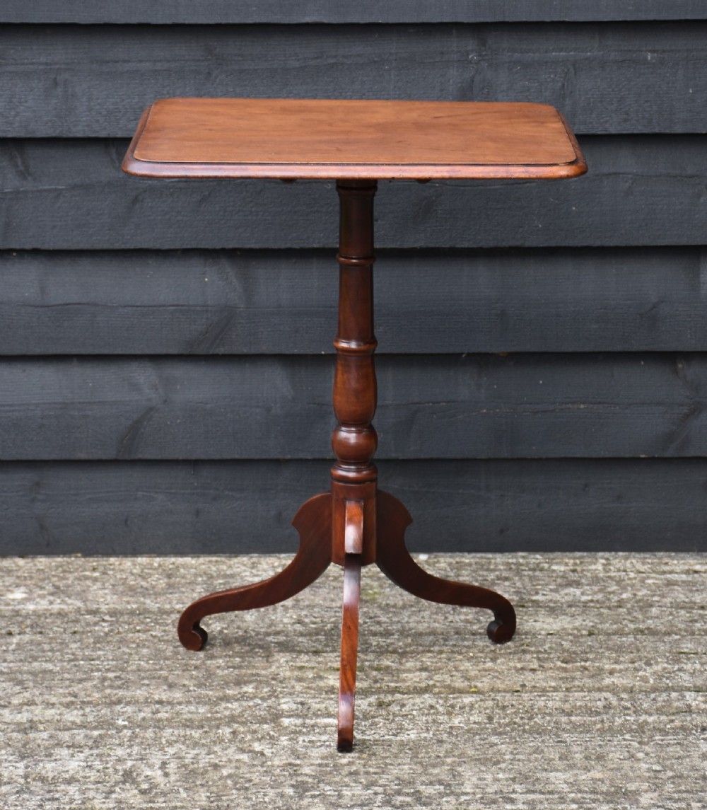 A 19th-century mahogany tilt-top wine table with a rectangular rounded surface, turned pedestal column, and three splayed legs.