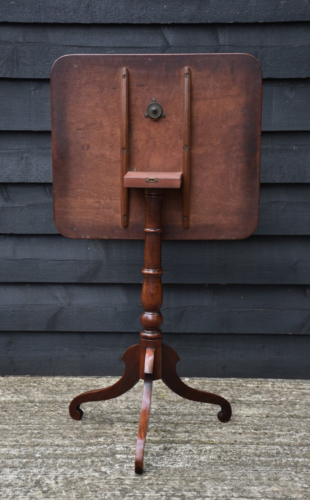 A 19th-century mahogany tilt-top wine table with a rectangular rounded surface, turned pedestal column, and three splayed legs. View III