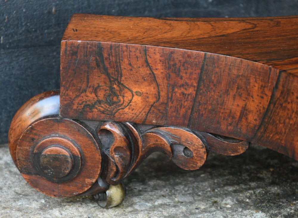 A 19th-century rosewood tea table featuring a rectangular fold-over top, carved scroll brackets, a tapered pedestal column, and a quadform plinth base with scroll feet. View VII