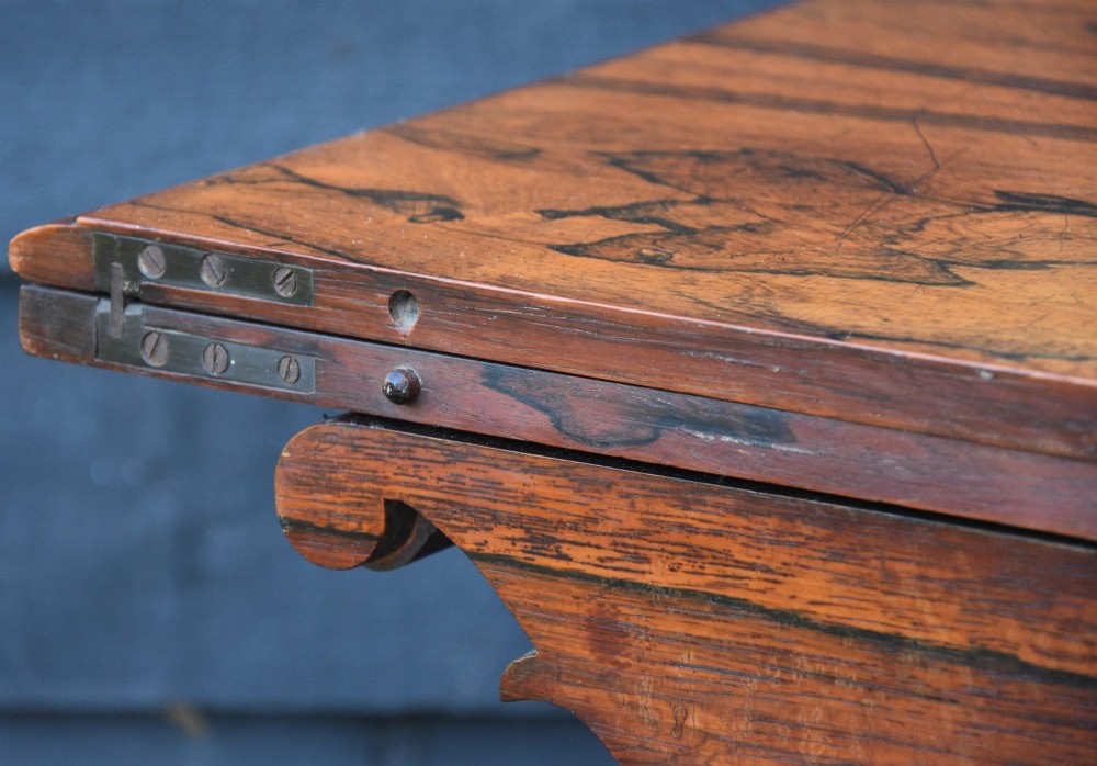 A 19th-century rosewood tea table featuring a rectangular fold-over top, carved scroll brackets, a tapered pedestal column, and a quadform plinth base with scroll feet. View VIII