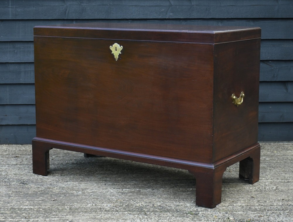 A Georgian mahogany travelling chest featuring side brass carrying handles, an escutcheon lock, and raised bracket feet. View II
