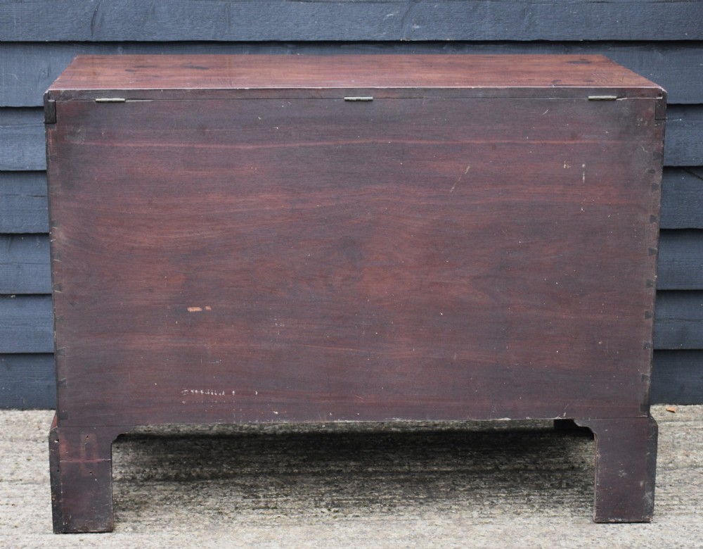A Georgian mahogany travelling chest featuring side brass carrying handles, an escutcheon lock, and raised bracket feet. View V
