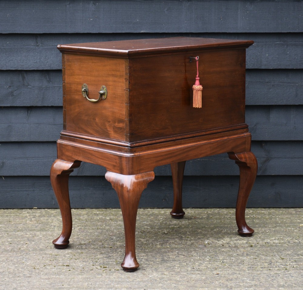 A 19th-century mahogany box on stand featuring cabriole legs, pad feet, brass side carrying handles, and a key with a pink tassel.