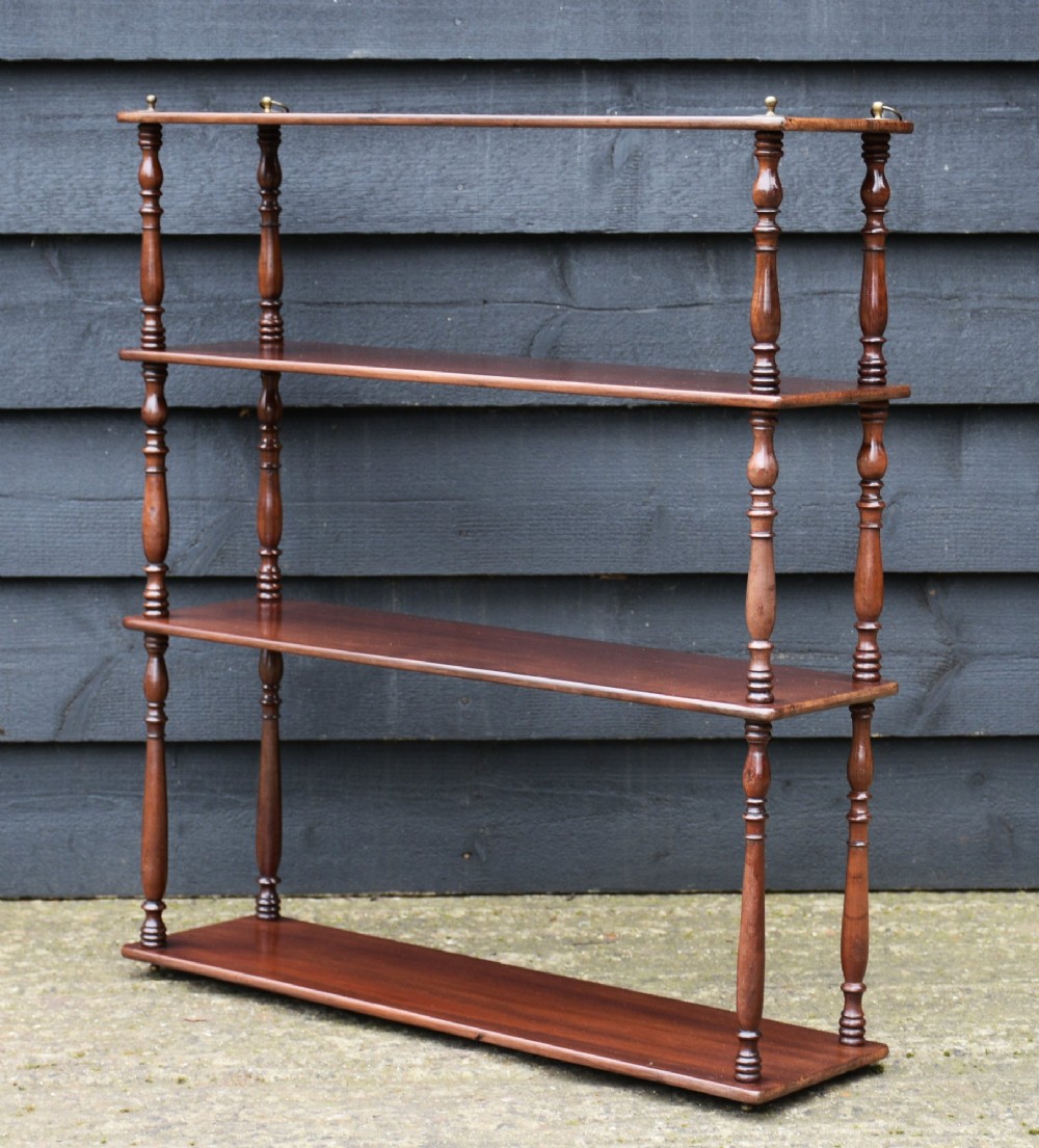 A four-tier Victorian mahogany hanging wall shelf unit featuring slim open shelves supported by slender turned spindles with brass mounting rings at the top. View II