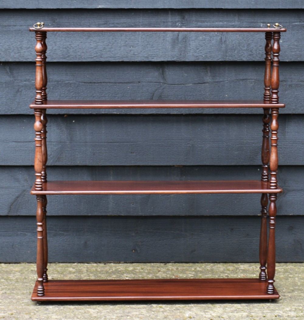 A four-tier Victorian mahogany hanging wall shelf unit featuring slim open shelves supported by slender turned spindles with brass mounting rings at the top. View III
