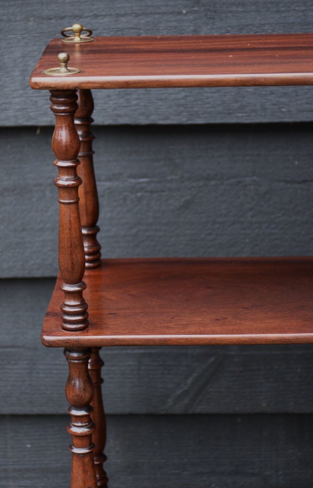 A four-tier Victorian mahogany hanging wall shelf unit featuring slim open shelves supported by slender turned spindles with brass mounting rings at the top. View V