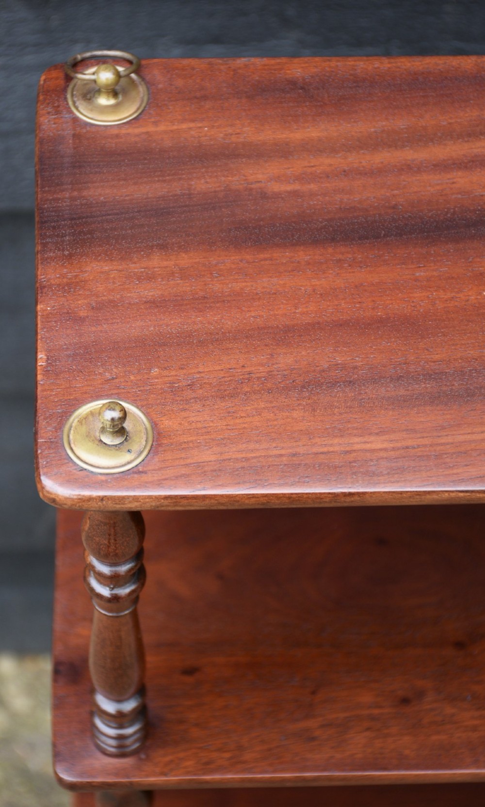 A four-tier Victorian mahogany hanging wall shelf unit featuring slim open shelves supported by slender turned spindles with brass mounting rings at the top. View VI