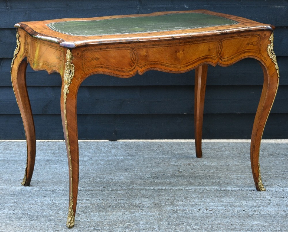 A nineteenth-century French kingwood writing desk featuring a serpentine top, marquetry inlay, slender cabriole legs, and ornate gilt bronze mounts. View VI