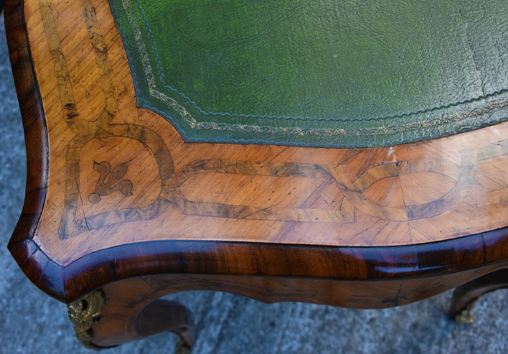 A nineteenth-century French kingwood writing desk featuring a serpentine top, marquetry inlay, slender cabriole legs, and ornate gilt bronze mounts. View VII