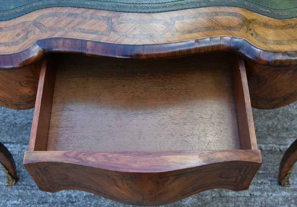 A nineteenth-century French kingwood writing desk featuring a serpentine top, marquetry inlay, slender cabriole legs, and ornate gilt bronze mounts. View IX