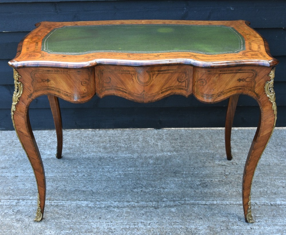 A nineteenth-century French kingwood writing desk featuring a serpentine top, marquetry inlay, slender cabriole legs, and ornate gilt bronze mounts. View X