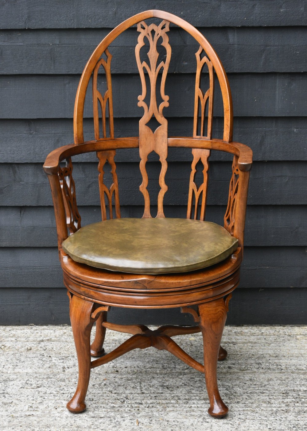 A carved walnut revolving desk chair featuring a Gothic pointed arch backrest with open tracery splats and cabriole legs. View II