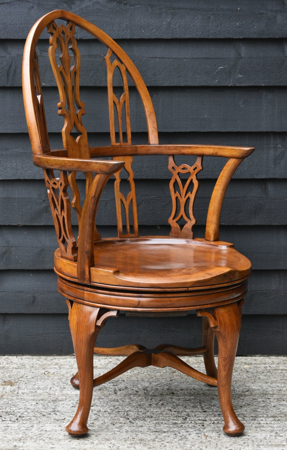 A carved walnut revolving desk chair featuring a Gothic pointed arch backrest with open tracery splats and cabriole legs. View V