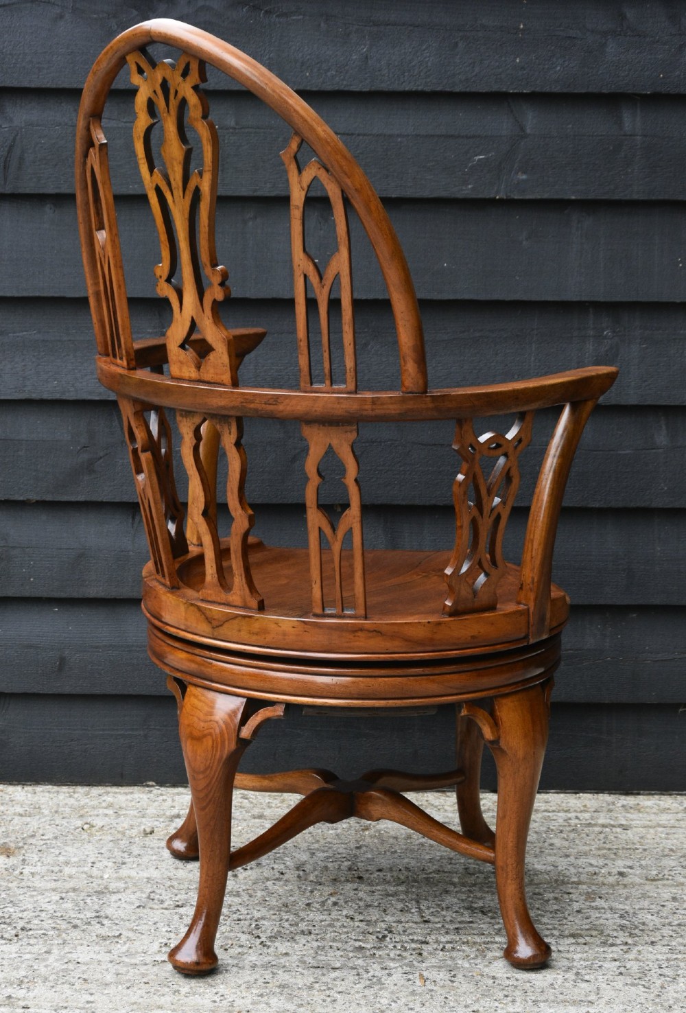 A carved walnut revolving desk chair featuring a Gothic pointed arch backrest with open tracery splats and cabriole legs. View VI