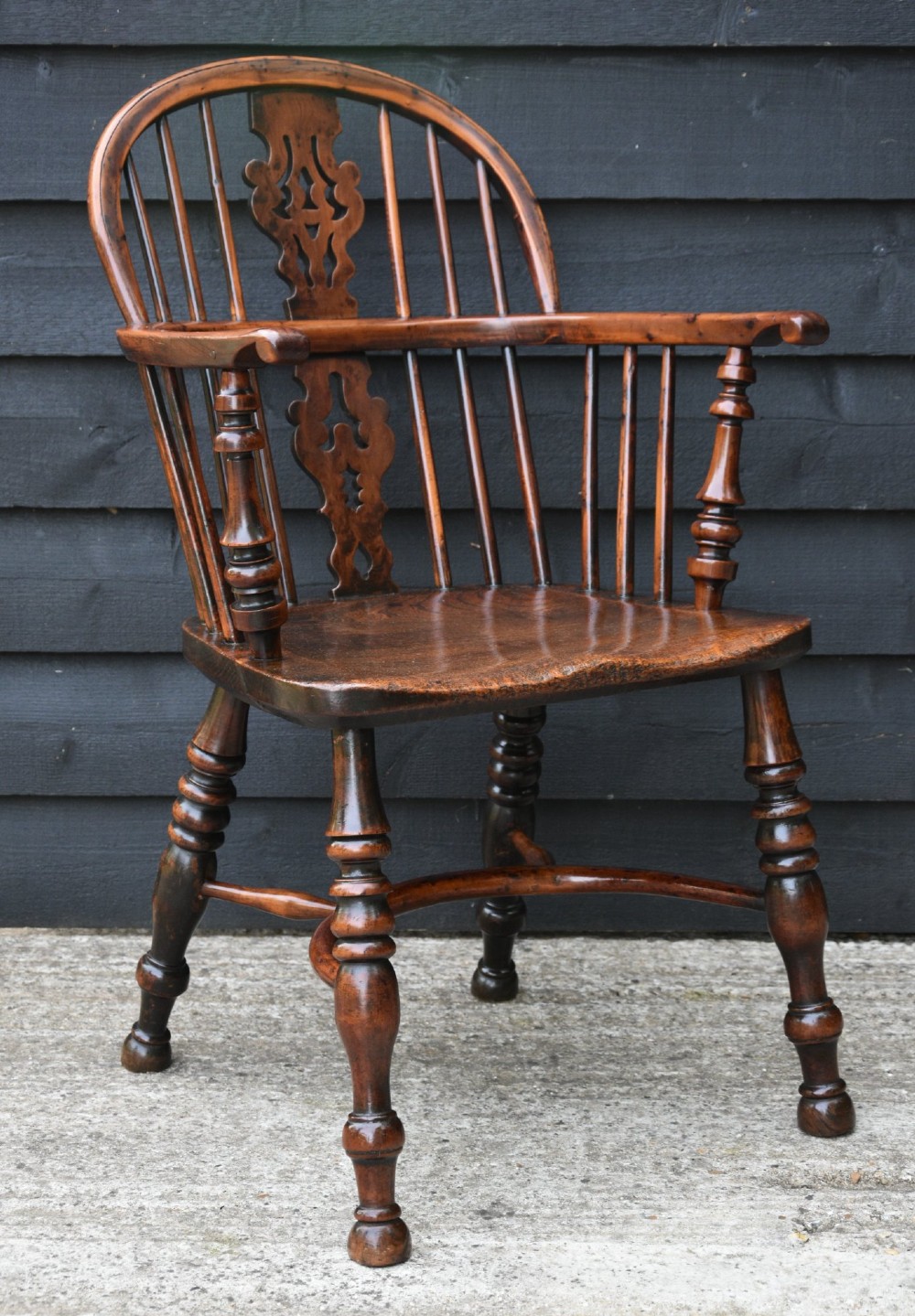 A matched pair of 18th-century Georgian yew and elm Windsor armchairs featuring curved hoop backs, pierced central splats, saddle seats, and turned legs. View II