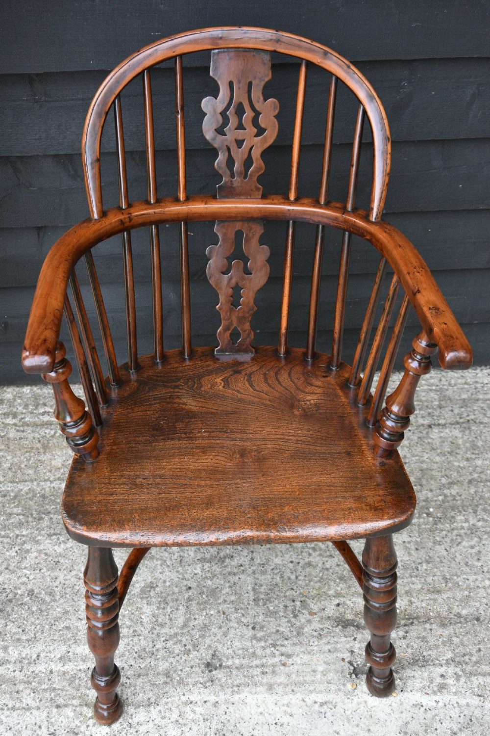 A matched pair of 18th-century Georgian yew and elm Windsor armchairs featuring curved hoop backs, pierced central splats, saddle seats, and turned legs. View V