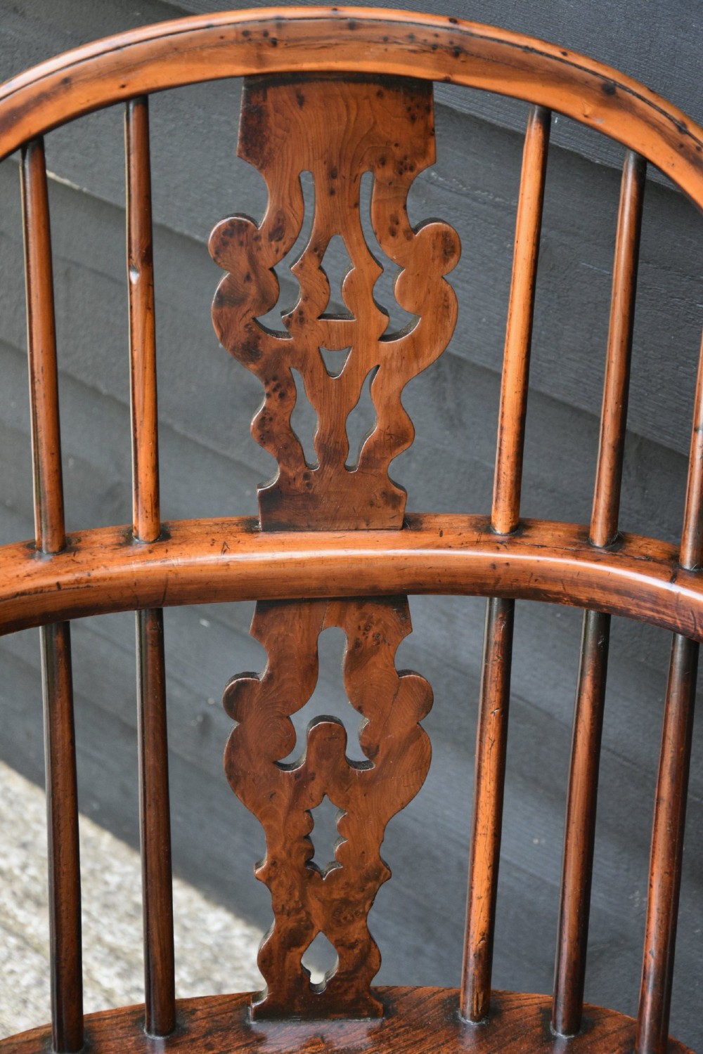 A matched pair of 18th-century Georgian yew and elm Windsor armchairs featuring curved hoop backs, pierced central splats, saddle seats, and turned legs. View VII