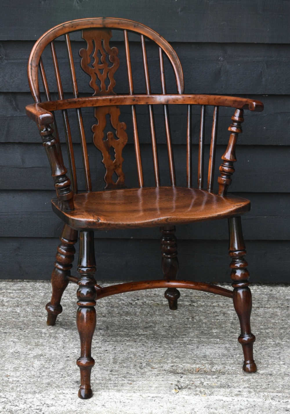A matched pair of 18th-century Georgian yew and elm Windsor armchairs featuring curved hoop backs, pierced central splats, saddle seats, and turned legs. View X