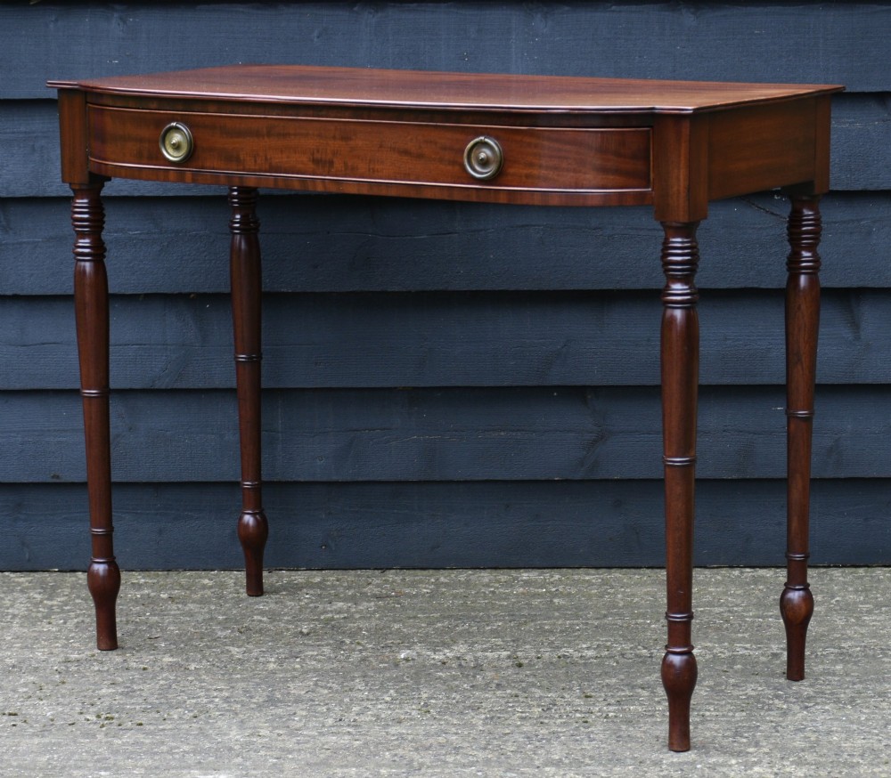 A Regency mahogany bow-fronted side table featuring a single drawer with brass ring handles and four turned tapered legs. View III