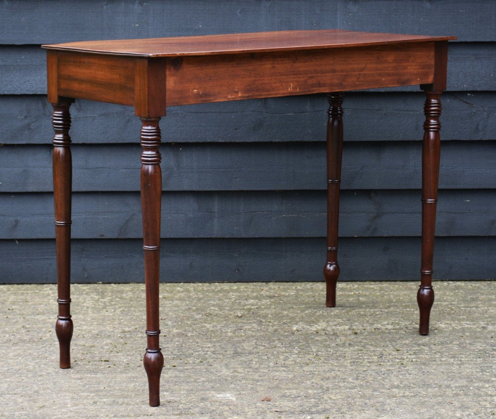 A Regency mahogany bow-fronted side table featuring a single drawer with brass ring handles and four turned tapered legs. View VI
