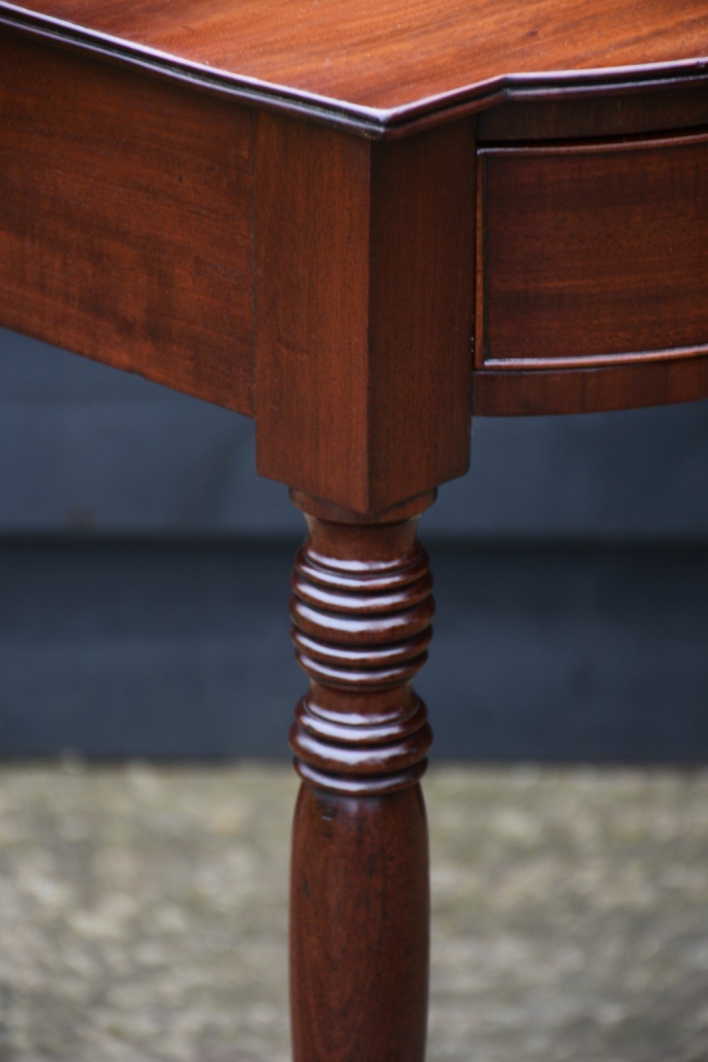 A Regency mahogany bow-fronted side table featuring a single drawer with brass ring handles and four turned tapered legs. View VIII