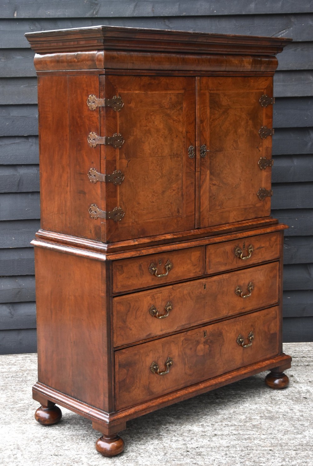 A seventeenth-century William and Mary walnut cabinet on chest featuring double doors with decorative brass hinges above three drawers on bun feet. View V