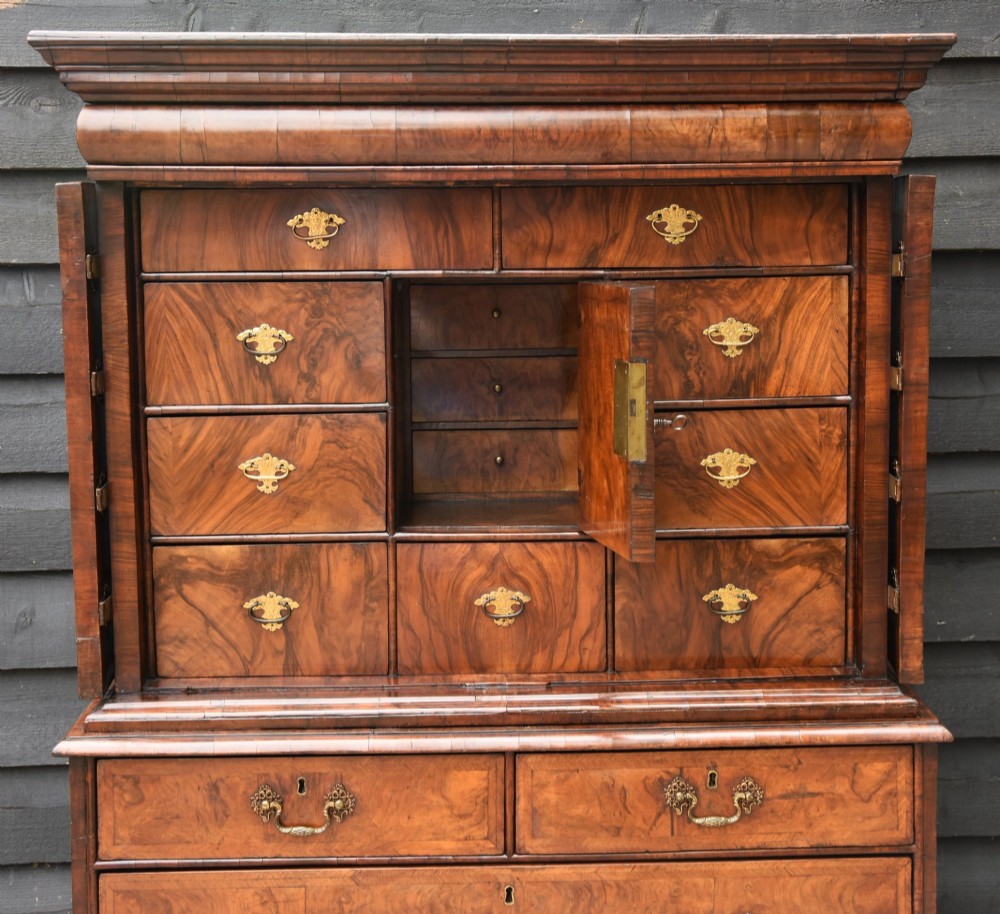A seventeenth-century William and Mary walnut cabinet on chest featuring double doors with decorative brass hinges above three drawers on bun feet. View VI