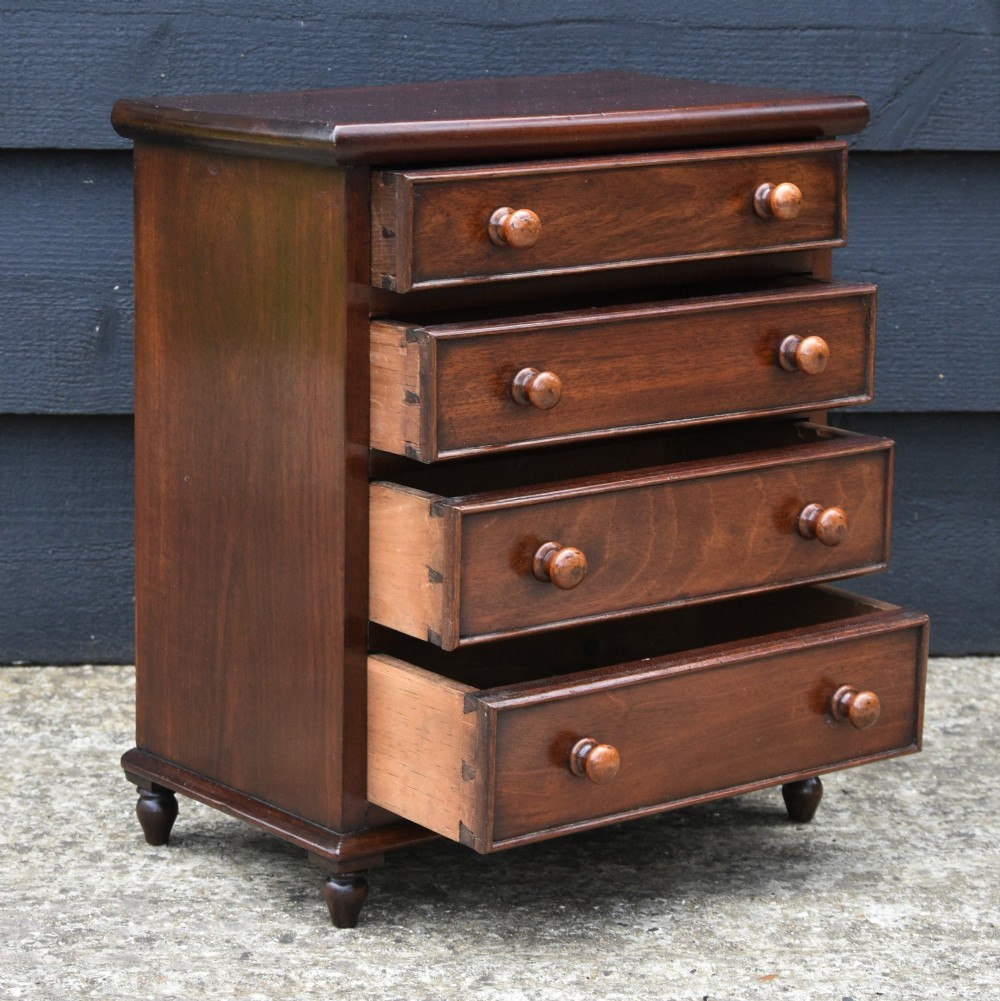 A Victorian mahogany miniature chest of drawers featuring four drawers with turned wooden knobs set upon short turned feet. View VI