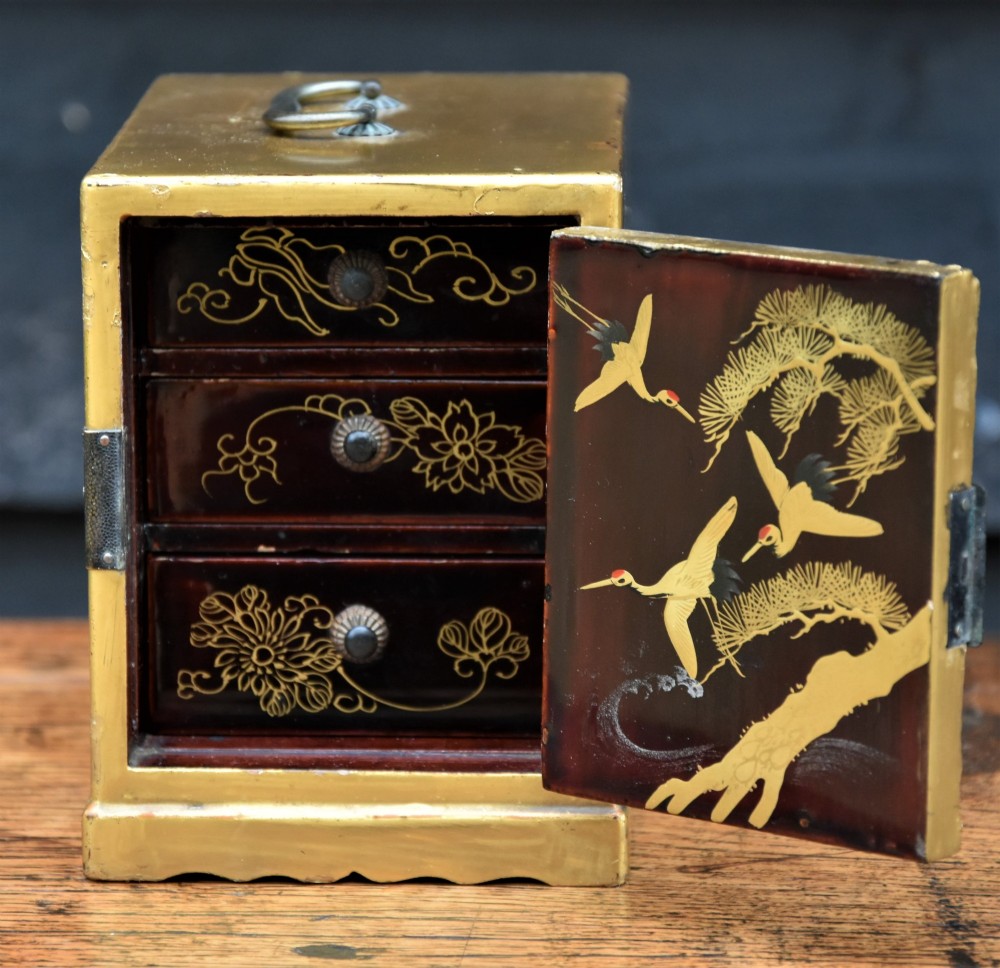 A small gold-lacquered Japanese cabinet featuring a single door with hand-painted bird and flower motifs and dark metal hinges. View VII