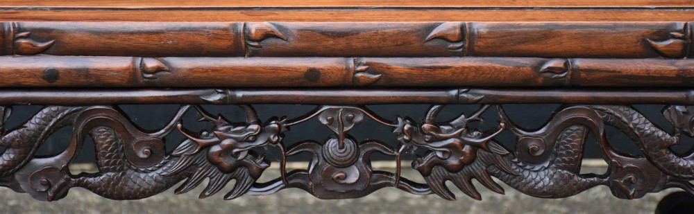 An antique Chinese rosewood low coffee table featuring elaborate openwork dragon carvings on the apron and curved scroll legs with bamboo motif borders. View II