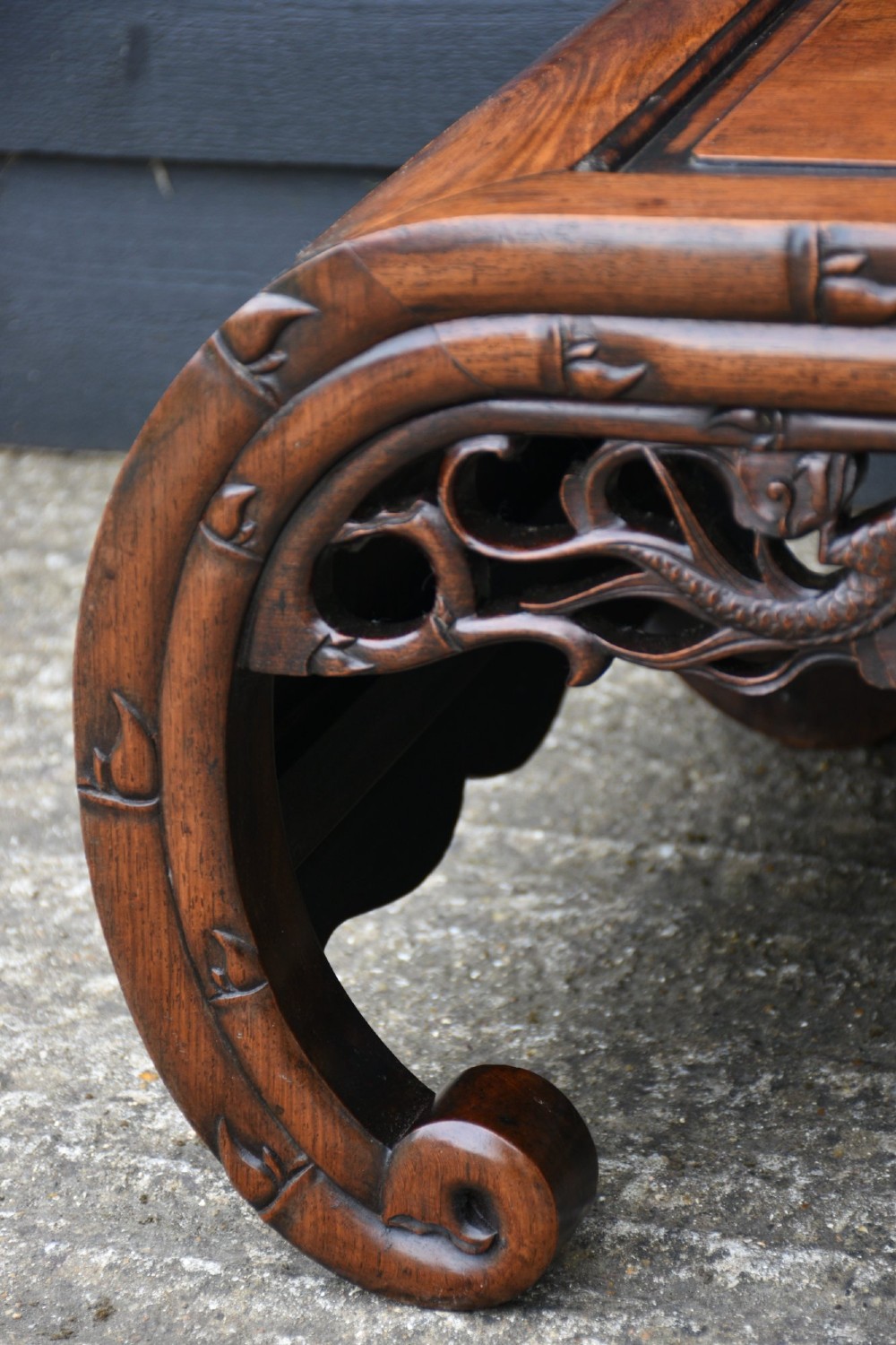 An antique Chinese rosewood low coffee table featuring elaborate openwork dragon carvings on the apron and curved scroll legs with bamboo motif borders. View VII