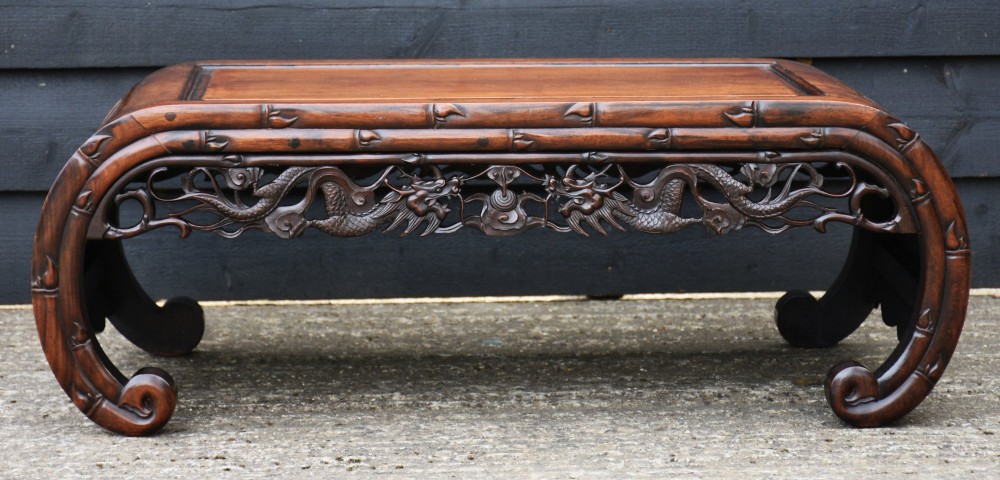 An antique Chinese rosewood low coffee table featuring elaborate openwork dragon carvings on the apron and curved scroll legs with bamboo motif borders. View VIII