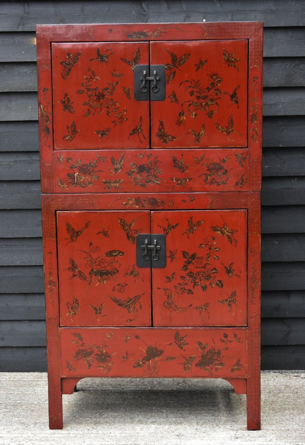 A two-tier red lacquered Chinese cabinet featuring hand-painted floral and butterfly details with black frame framing and dark metal door hardware. View VIII
