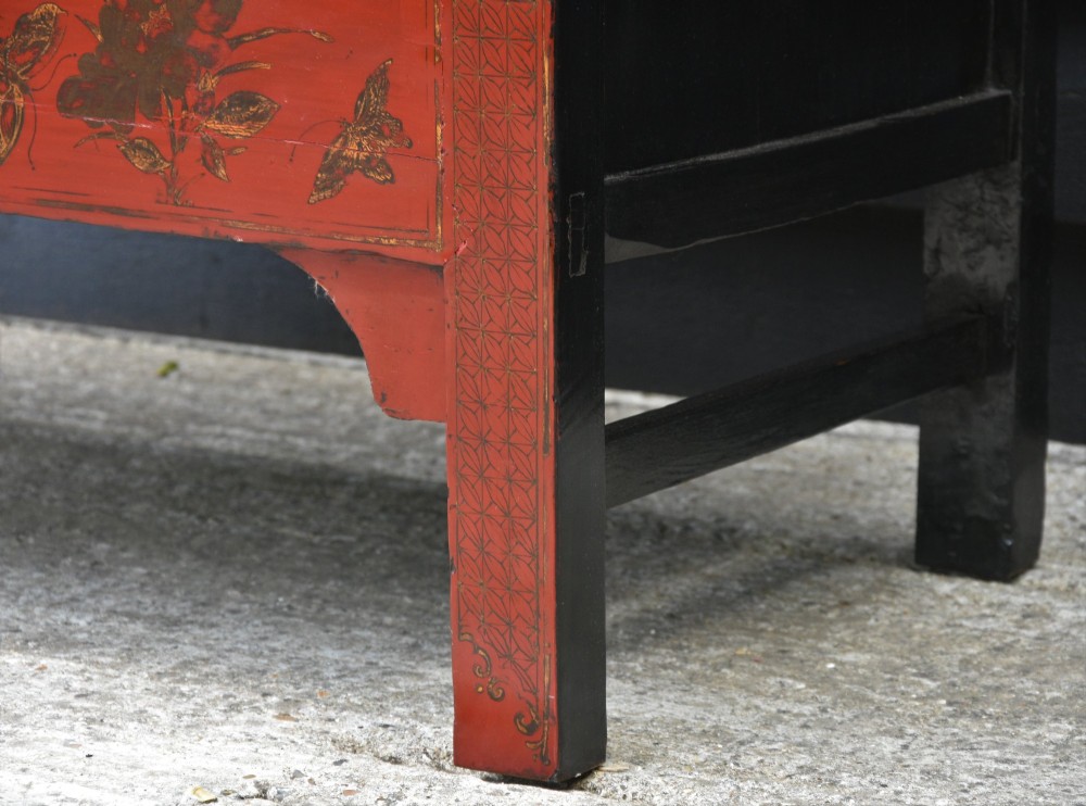 A two-tier red lacquered Chinese cabinet featuring hand-painted floral and butterfly details with black frame framing and dark metal door hardware. View IX