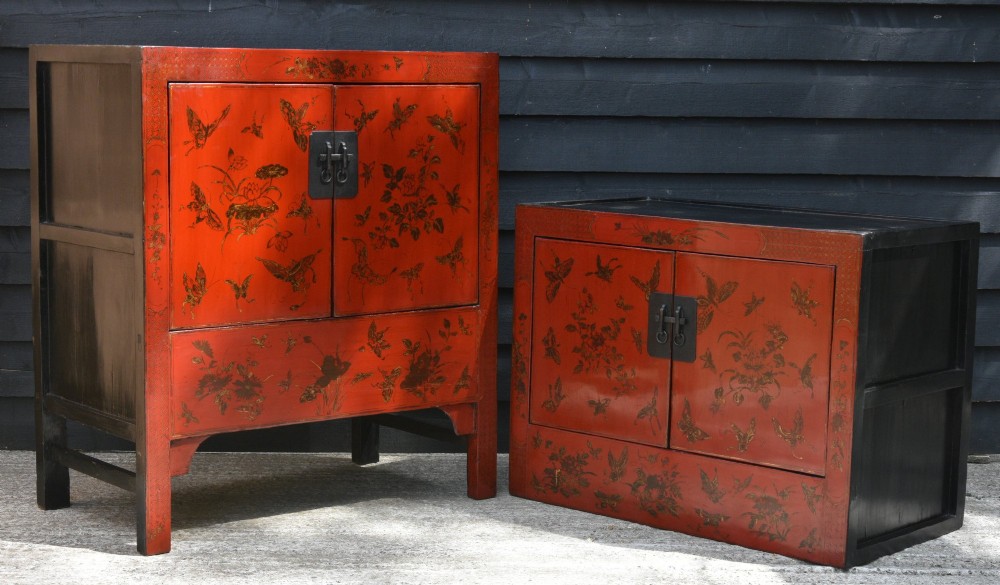 A two-tier red lacquered Chinese cabinet featuring hand-painted floral and butterfly details with black frame framing and dark metal door hardware. View X