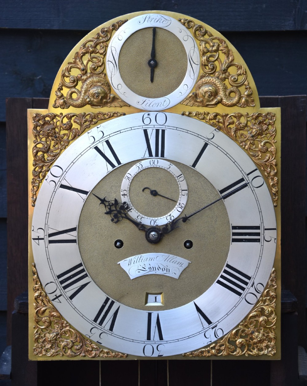 An 18th-century Georgian longcase clock in flame mahogany with an arched brass dial and brass finials. View IV