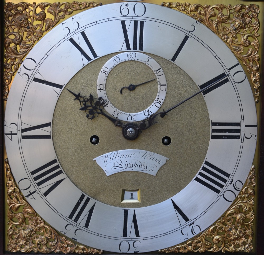 An 18th-century Georgian longcase clock in flame mahogany with an arched brass dial and brass finials. View V