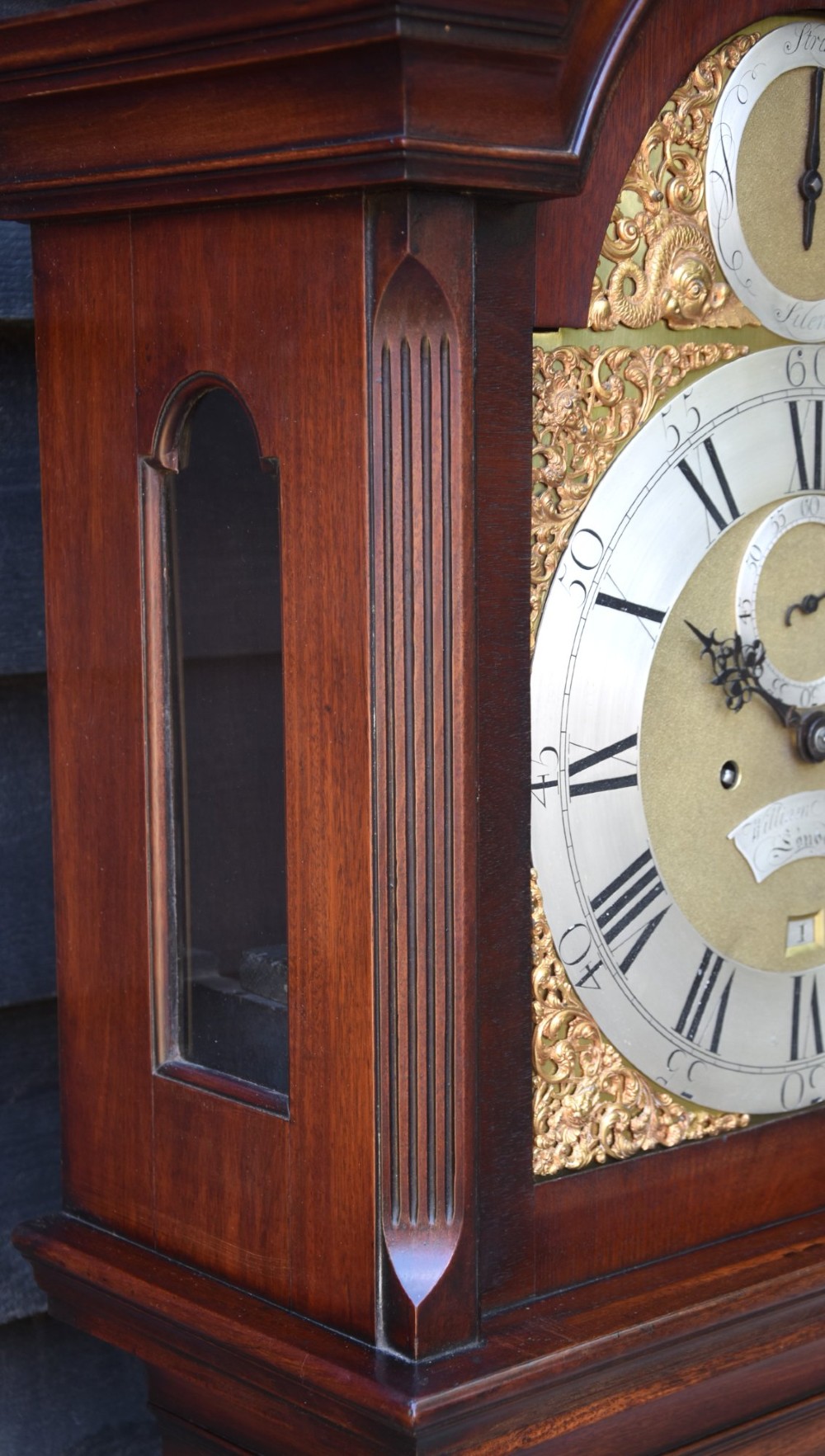 An 18th-century Georgian longcase clock in flame mahogany with an arched brass dial and brass finials. View IX