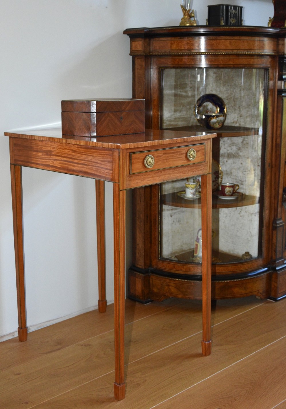 A Georgian satinwood lamp table featuring a single frieze drawer with brass handles and slender square tapered legs.
