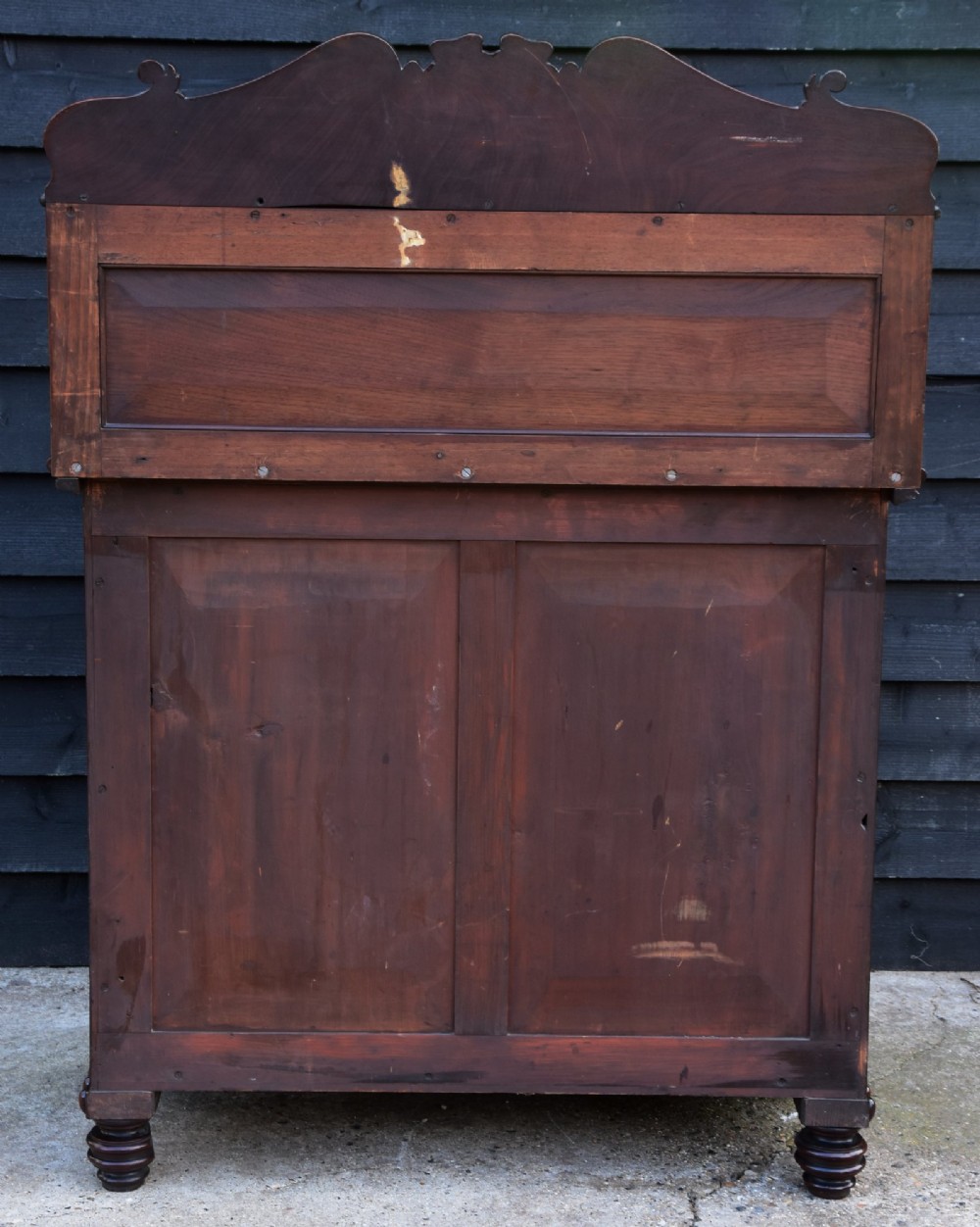 A Regency mahogany chiffonier cabinet featuring an ornate carved shell crest shelf, frieze drawer, two cupboard doors with flame mahogany panels, and turned feet. View X