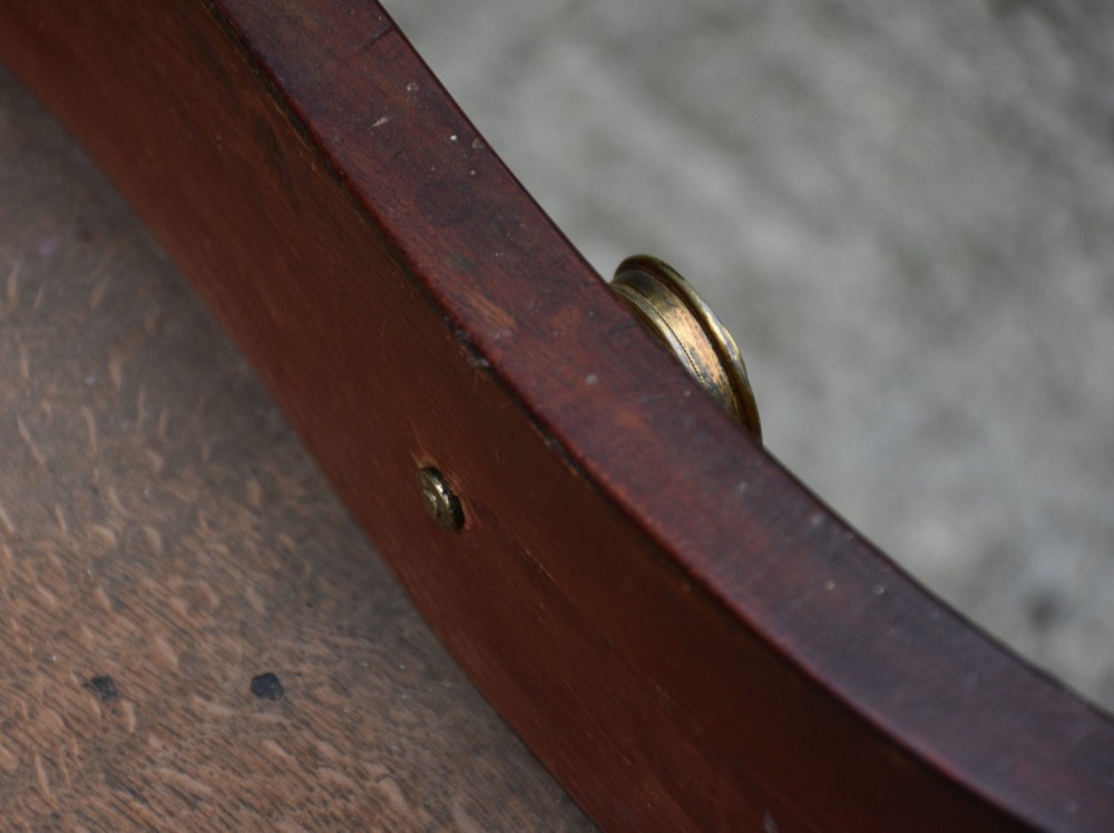 A late 18th-century Georgian serpentine chest of drawers crafted from flame mahogany with satinwood crossbanding, four graduated drawers, brass knobs, and bracket feet. View VII