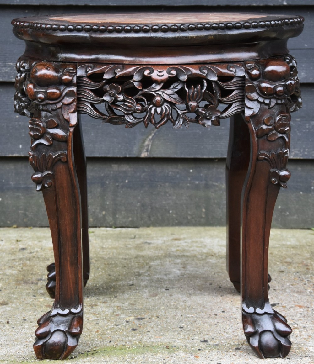 A 19th-century Chinese carved rosewood low plant stand featuring a circular marble insert top, an intricately pierced mask apron, cabriole legs, and claw feet. View III