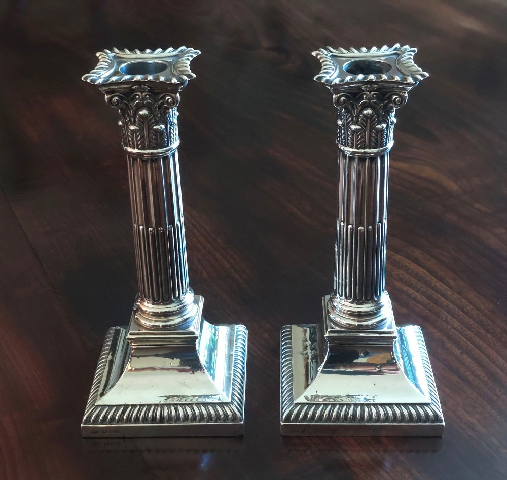 A pair of sterling silver Corinthian column candlesticks featuring fluted shafts, acanthus leaf capitals, and gadrooned square bases. View VII