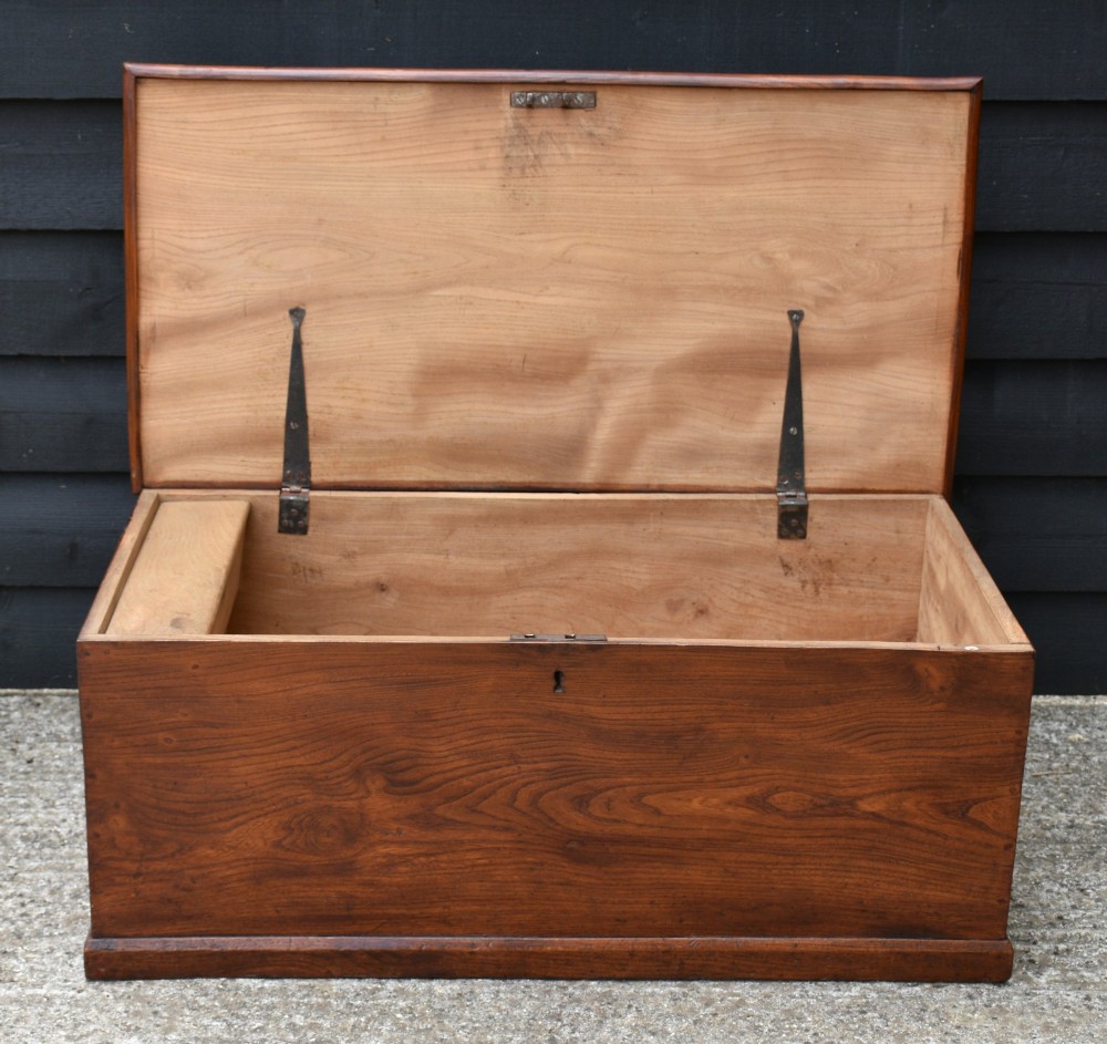 A low rectangular Georgian elm blanket box with a hinged lid, prominent wood grain, central keyhole, and iron side handles. View VI