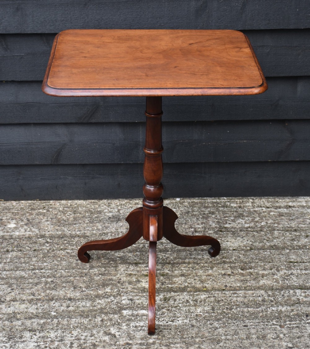 A 19th-century mahogany tilt-top wine table featuring a rectangular rounded top, turned central column, and a tripod base.