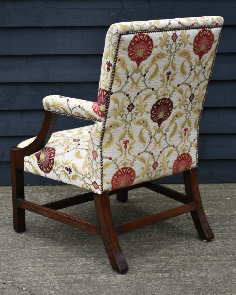 A Georgian Gainsborough armchair featuring cream and red floral upholstery, open mahogany arms, and a solid timber frame with stretchers. View IV