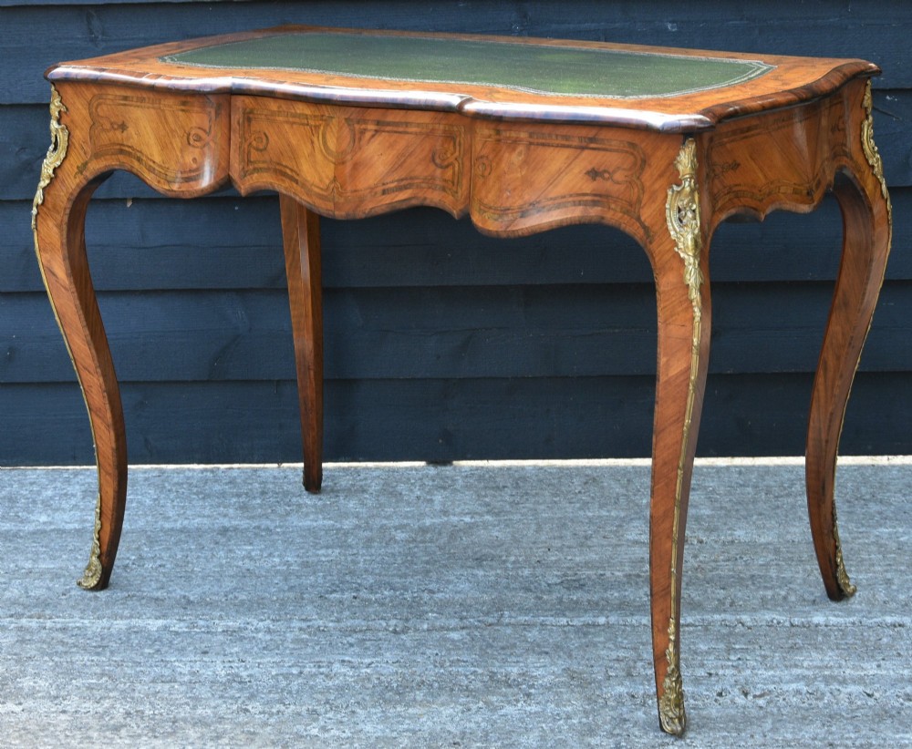 A 19th-century French kingwood writing desk featuring a green leather top, serpentine sides, marquetry inlay, and gilt bronze mounts. View V