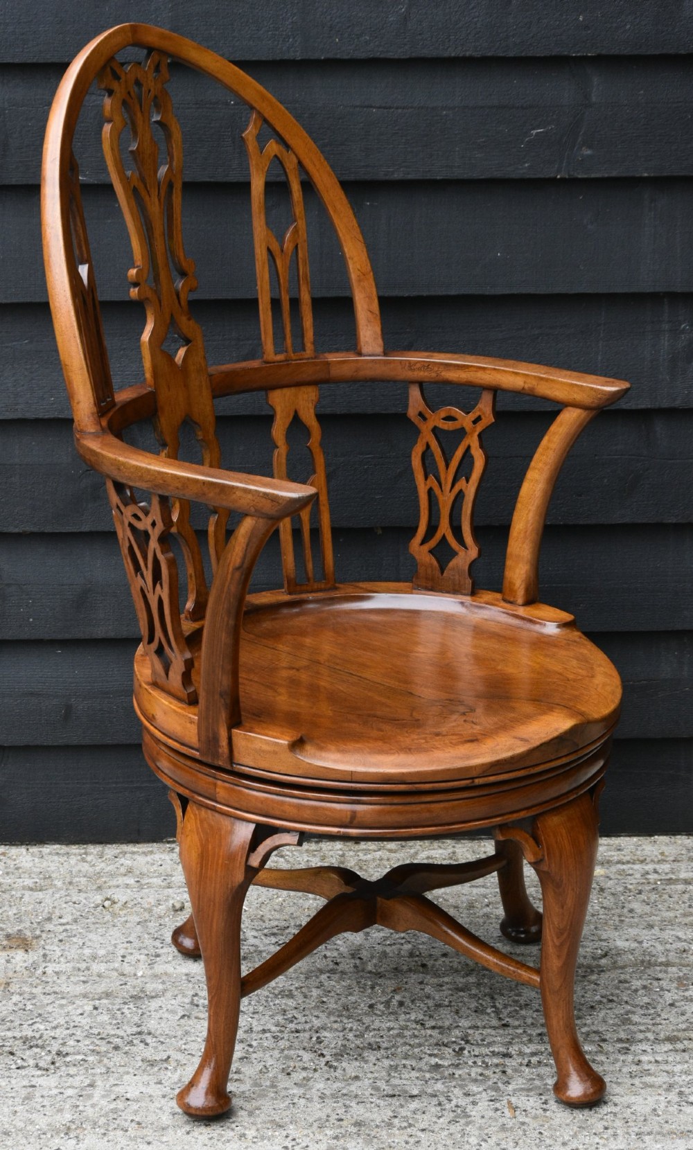 A Victorian Gothic Revival walnut revolving desk chair featuring a pointed arched backrest with decorative carved tracery and cabriole legs. View V